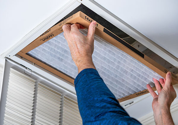 Man replacing dirty HVAC air filter in ceiling vent. Home air du